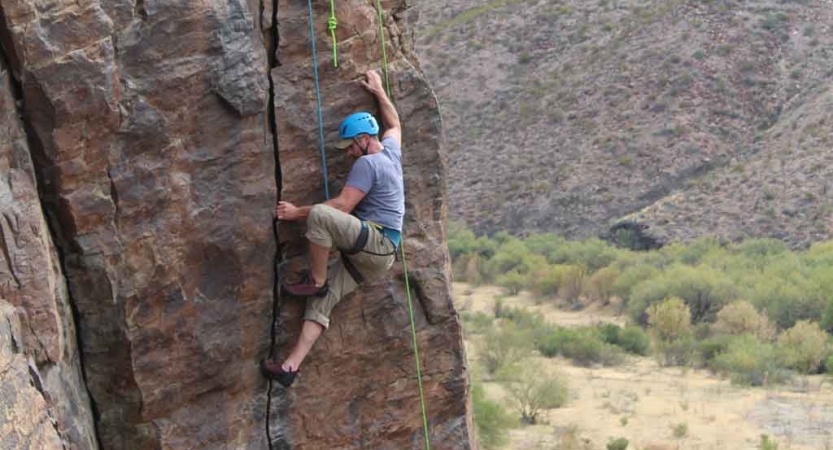 a gap year student climbs a rock wall on an outward bound semester course